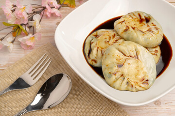 Steamed Chives Dumplings or Leek Stuffed Dough, steamed dumpling stuffed with sliced garlic chives soaked in special soy sauce serving in a bowl. It is called 