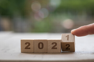 Happy New Year 2021 to 2022 wooden blocks turning finger green background