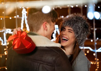 Cute young couple , Boyfriend giving his girlfriend present in magically lit city street 