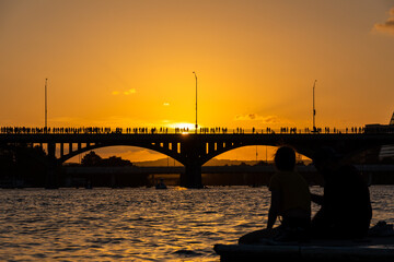 Austin Texas Congress Bridge summer Sunset before the bats fly, silhouette of couple sitting on...