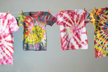 Four T-shirts are dried after coloring in tie dye style. Flat lay.