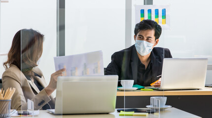 Social distancing working office during coronavirus pandemic outbreak quarantine, businessman and businesswoman in formal suit wearing safety face mask keeping space working together in workplace