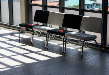 Shadow and light shot of waiting chairs in company office workplace during coronavirus quarantine pandemic outbreak marked with red cross marker sign to avoid human contact for safety social distance