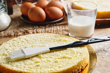 Impregnation with a milk of vanilla biscuit with a silicone brush. Baking a sponge biscuit cake. Cooking homemade cake. Home confectionery.