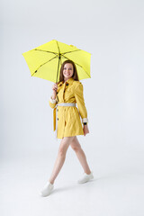 Beautiful young woman with umbrella standing in studio