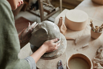 Close-up of designer making sculpture of human face from clay in the ceramic studio