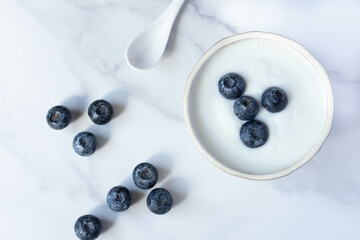 fresh blueberry yogurt in white cup on marble background