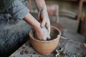 Fototapeta premium Close-up of pottery artist washing her hands of clay in bowl after work