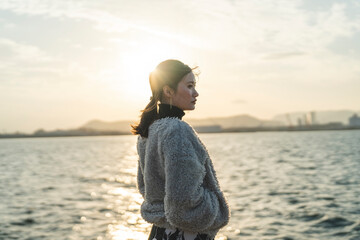 冬の夕暮れの海にいる女性