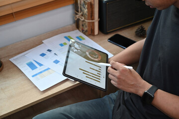 Young man analyzing financial graph on digital tablet.