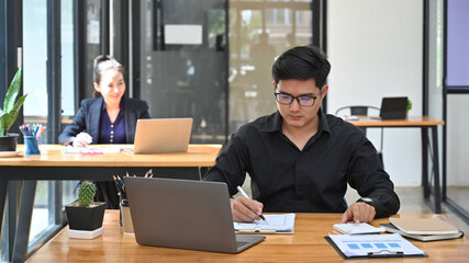 Asian businessman working with financial documents and using calculator.