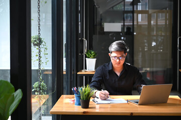 Young focused businessman analyzing statistical data at office desk.
