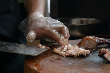 Close up of chef slicing roasted chicken on wooden cutting board. Chef preparing grilled chicken. Dicing chicken meat.