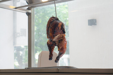 Hanged roasted chicken in restaurant. Grilled Chicken showcase hanged on hook. Chinese restaurant dish.
