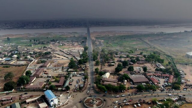 Highway, roundabout and bridge with the Benue River and densely populated city on the horizon in Nigeria, West Africa - aerial view