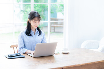 Fototapeta premium Beautiful Japanese woman working on computer with her head down, copy space available, wide angle, overhead view.