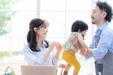 リモートで忙しいママから赤ちゃんを受け取るパパ