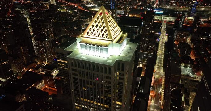 Aerial tilt down at night of skyscraper building. BNY Mellon office building with triangle on rooftop.