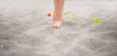 Bare feet on the beach sand. Tennis balls. Sport.