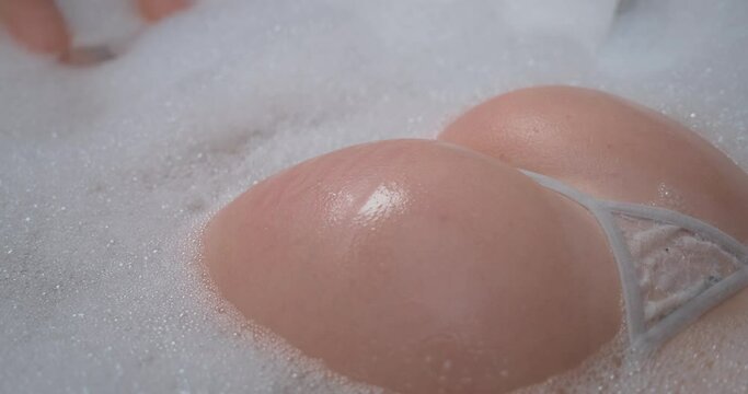 Sexy Round Ass In Thong Of A Hot Woman In The Bathtub, Tapped By A Hand While Bathing. close up