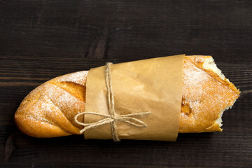 Baguette. Fresh golden baguette on an old wooden table. Close-up. French traditional bread on a dark background. Top view. Copy space. - 477240898
