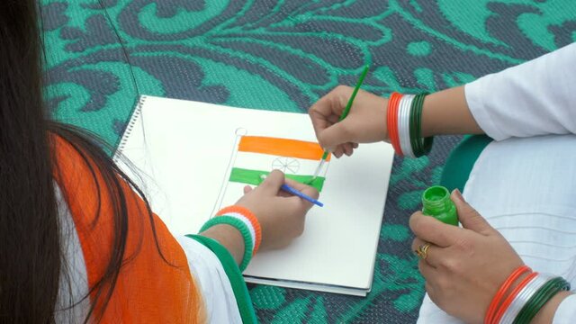Closeup shot of painting the National Flag - Tricolor in the flag. Two best friends wearing Tricolor Bangles and armbands on the occasion of Republic Day - patriotism  gazetted holiday  traditional...