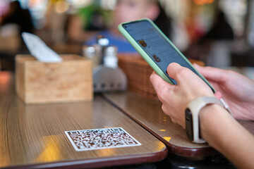 Closeup of guest hand ordering meal in restaurant while scanning qr code with mobile phone for...