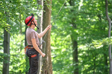 Man belays his partner climber with belaying device and rope. Climber's handsman holding equipment for rock mountaineering security.