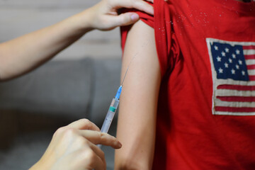 compulsory vaccination of children and adolescents. the doctor makes an injection in the hand of...