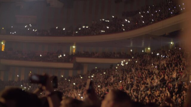 Audience waving hands and mobile flashlights at the concert