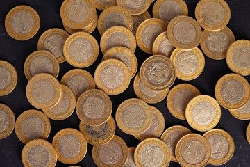 10 mexican peso coins on black background