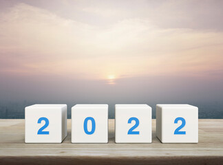2022 letter on white block cubes on wooden table over modern city tower and skyscraper at sunset, vintage style, Happy new year 2022 cover concept