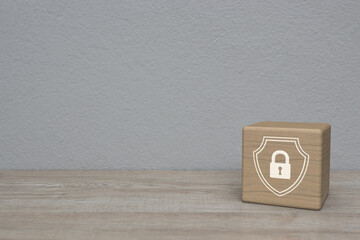 Padlock with shield flat icon on wood block cube on wooden table over white wall background,...