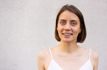 Beautiful woman with braces on her teeth on a beige background. Correction of bite and crooked...