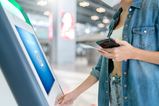 smart asian female traveller self checking in for flight transport at gate counter machine scaning monitor device at airport check in counter,smart technology travel ideas concept at terminal