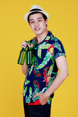 Young Asian man in casual and hat for beach party, smile and happy with two glass bottles of alcoholic drinks in hand