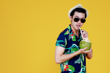 Handsome Asian guy in summer casual, smart sunglasses and hat enjoy drinking sweet juice from fresh...