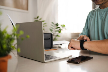Working all day, close-up of man wearing smart watch using laptop