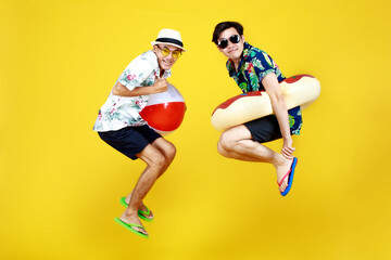 Fototapeta na wymiar Young naughty guys in hot summer dresses acting funny jump with float ball and swimming tube as enjoy beach vacation with outdoor recreation game to play with happy friend