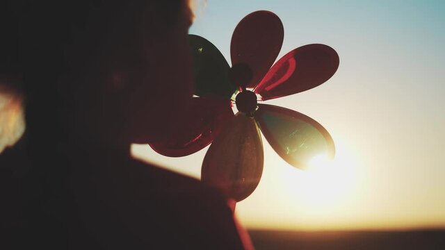 kid pinwheel. little baby girl silhouette play with windmill toy wind in the park. happy family kid dream concept. baby girl fun play toy pinwheel the glare sunset of the sun at in the park