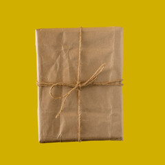 gift made of kraft paper tied with thine on a dark yellow background