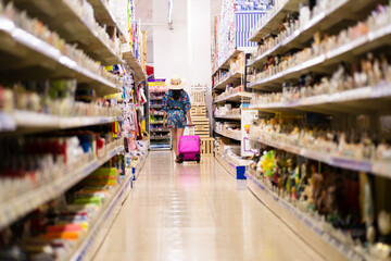 Supermarket full of products with a woman in dress and a suitcase walking arround