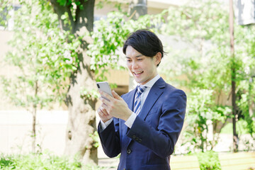 ビジネスマン　スマホ　屋外