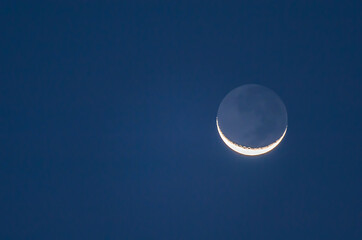 Naklejka na ściany i meble The crescent moon shines in the night-blue sky.