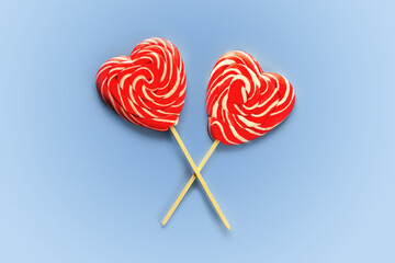 Two crossed red heart lollipops on blue background love and Valentine day background