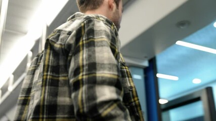 Handheld, young guy rides the subway and reads a book, a student goes to study at the university, morning on the public transport, the guy gets off the train.