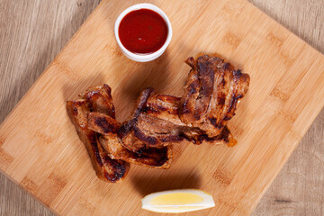 Delicious grilled ribs with red sauce on wooden board