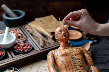 Acupuncture models and medical books are on the table. Acupuncture is a traditional Chinese medical method
