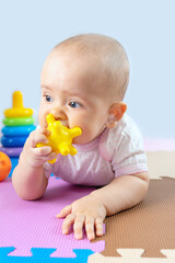 A newborn baby chews on a yellow silicone toy. Teething in babies