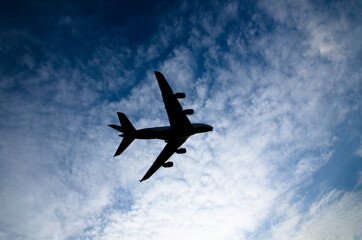 Silhouette of an airplane flying isolated on cloudy sky day background.